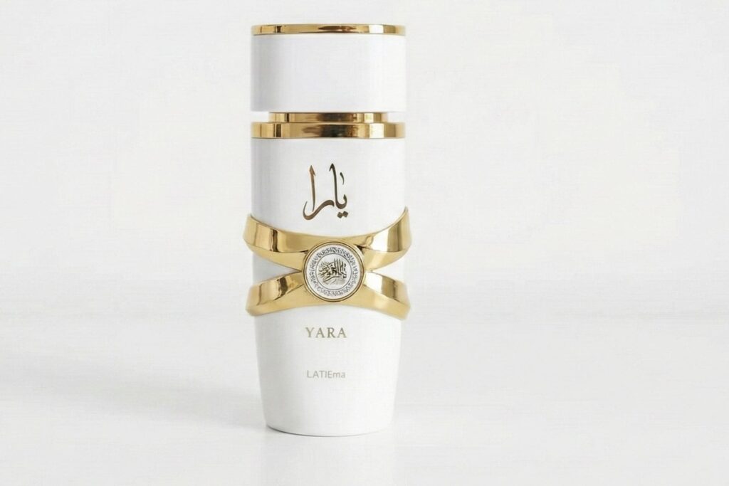 Frasco del perfume árabe Yara de Lattafa, con diseño cilíndrico en blanco y detalles dorados, incluyendo caligrafía árabe y el nombre 'YARA' en el frontal, sobre fondo blanco liso.